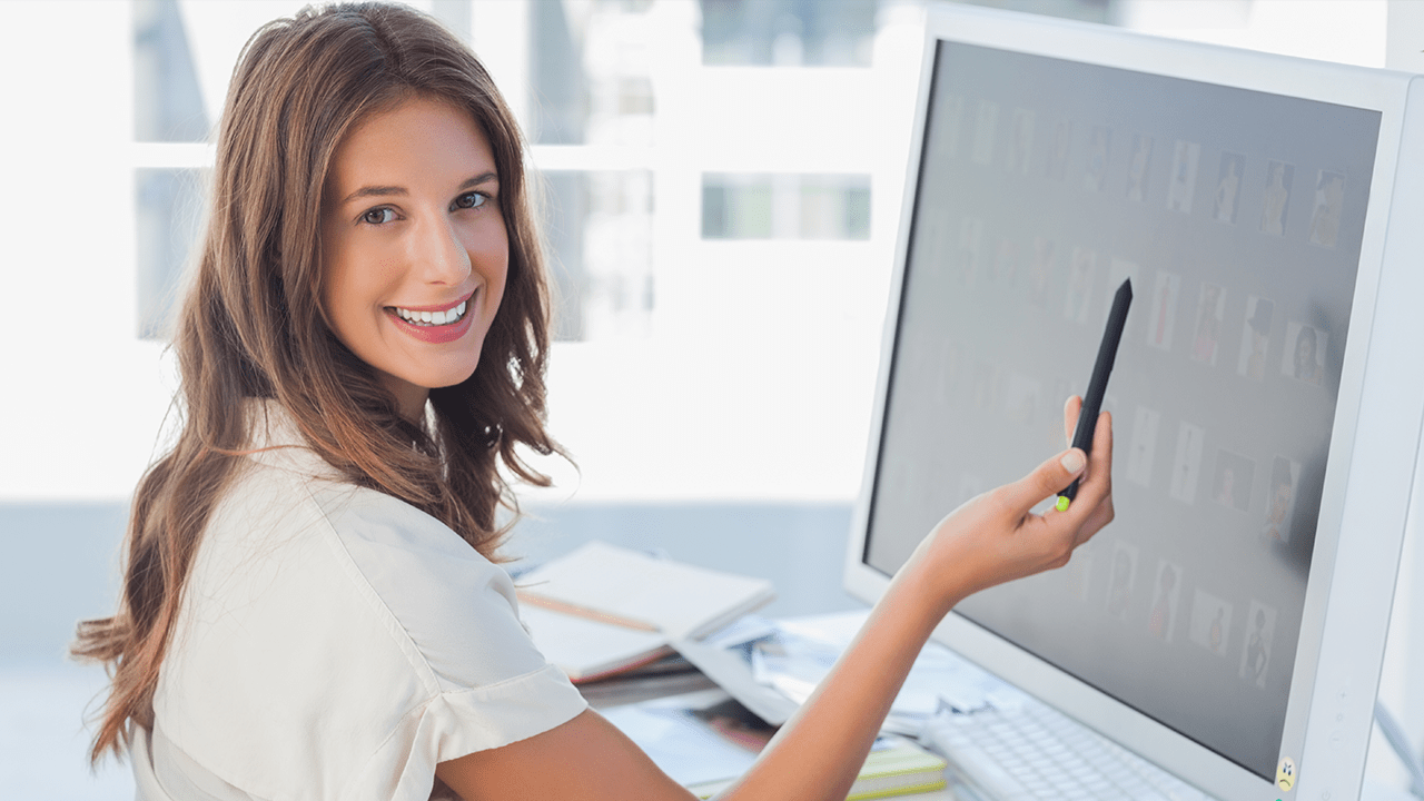 Frau zeigt auf Computerbildschirm auf dem eine Bildbearbeitung stattfindet